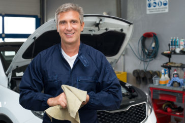 Portrait Of A Happy Auto Mechanic Cleaning Hands With Cloth